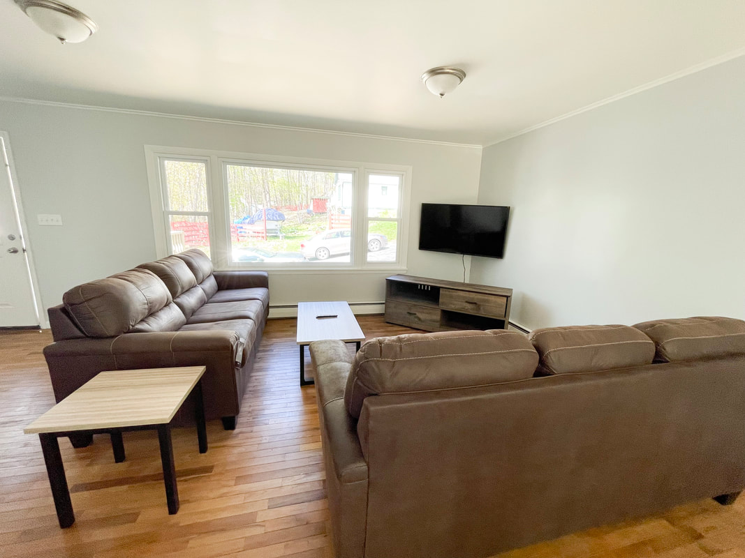Living room with two sofas, TV, and large windows